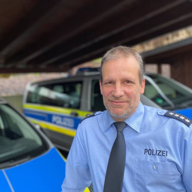 Polizeihauptkommissar Ludger Rath lehnt an einem Streifenwagen.