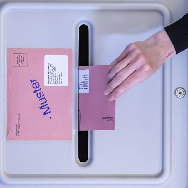 Eine Frau wirft den Umschlag mit dem Stimmzettel für die Europawahl in eine Wahlurne in der eröffneten Briefwahlstelle im Neuen Rathaus der Stadt Leipzig.