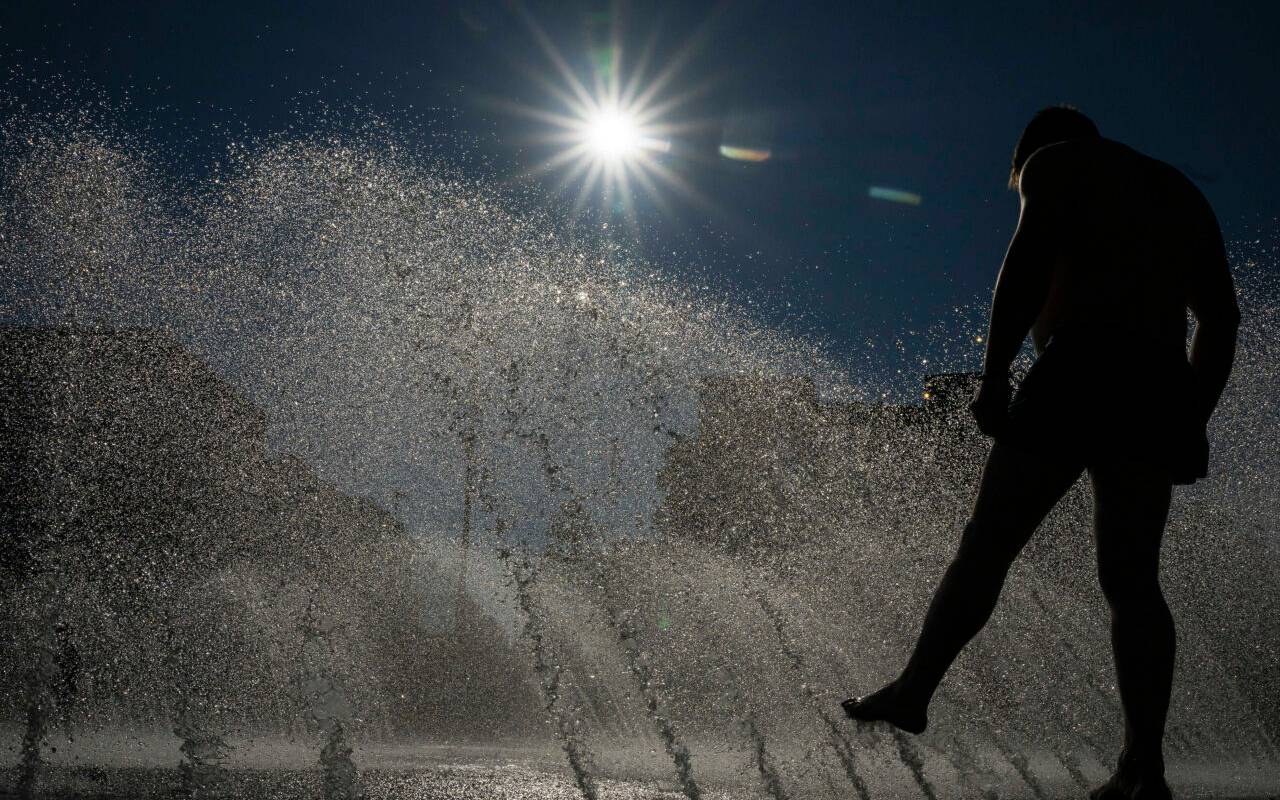 Ein Mann kühlt sich an einem Brunnen am Stachus in der Innenstadt im Wasser ab.