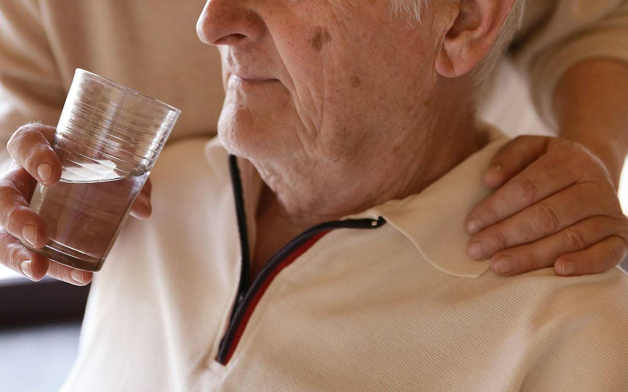 Eine Frau hilft einem Mann beim Trinken
