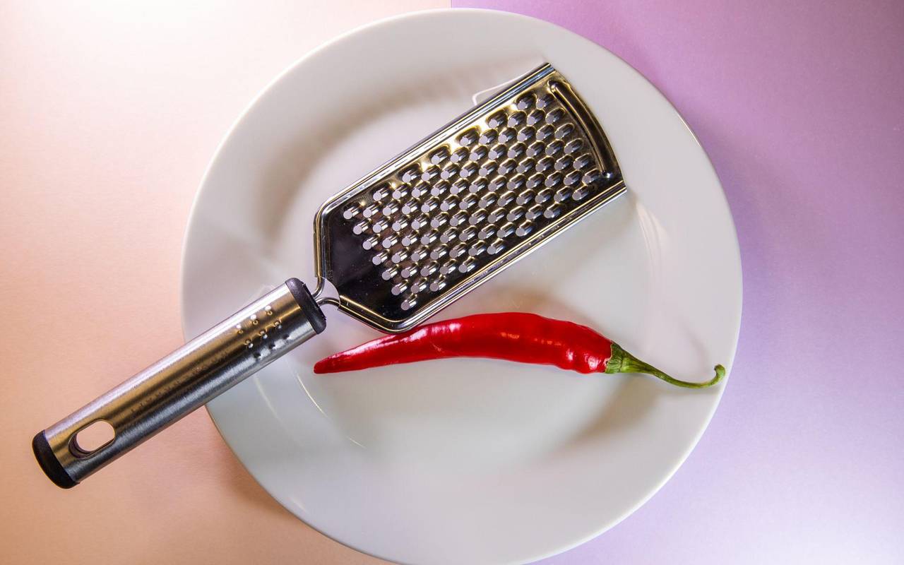 Chilischote liegt neben einer Küchenreibe