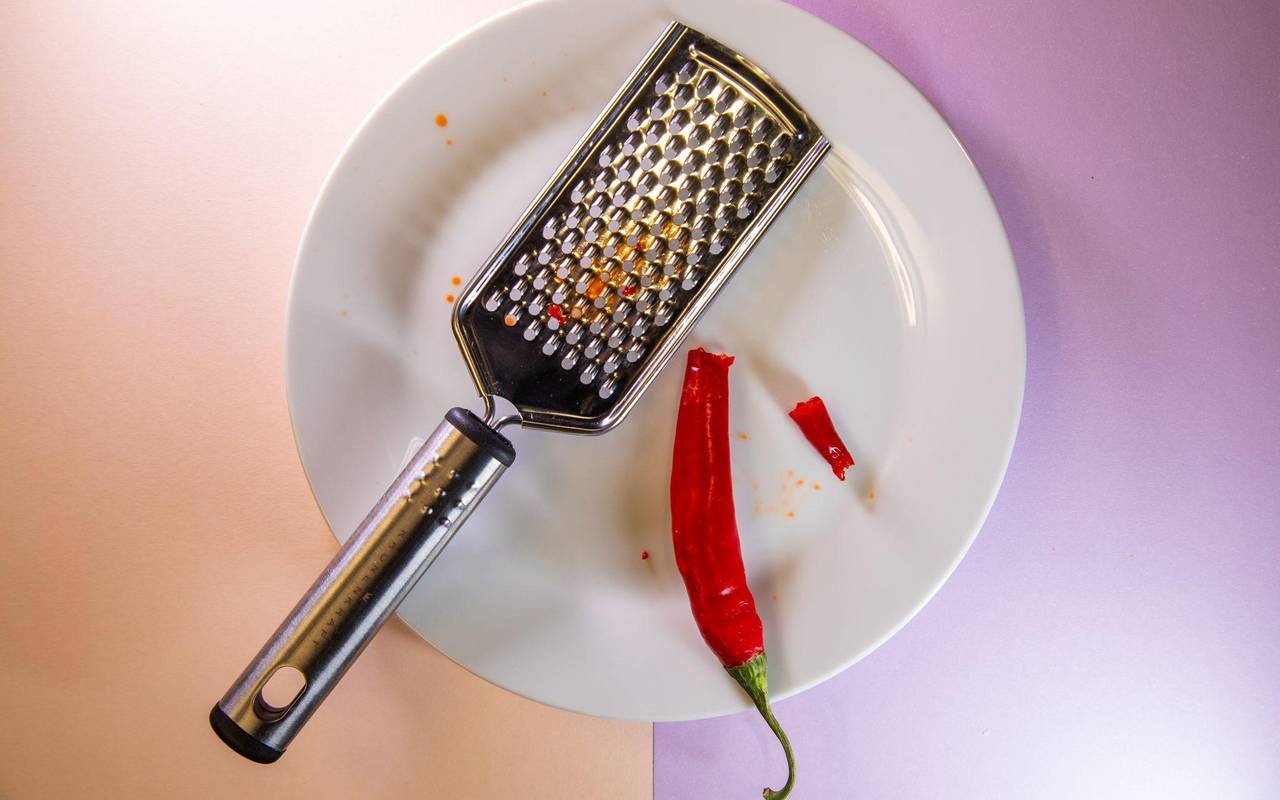 Gebrochene Chili liegt neben einer Küchenreibe