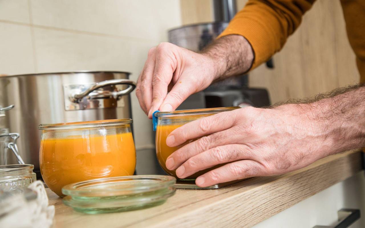 Ein Mann füllt Kürbismuß in Einweckgläser