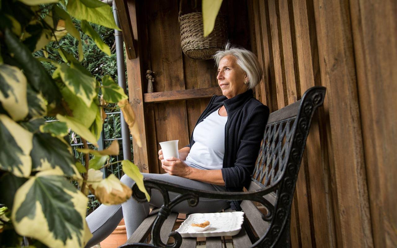 Eine ältere Dame sitzt in einem Garten