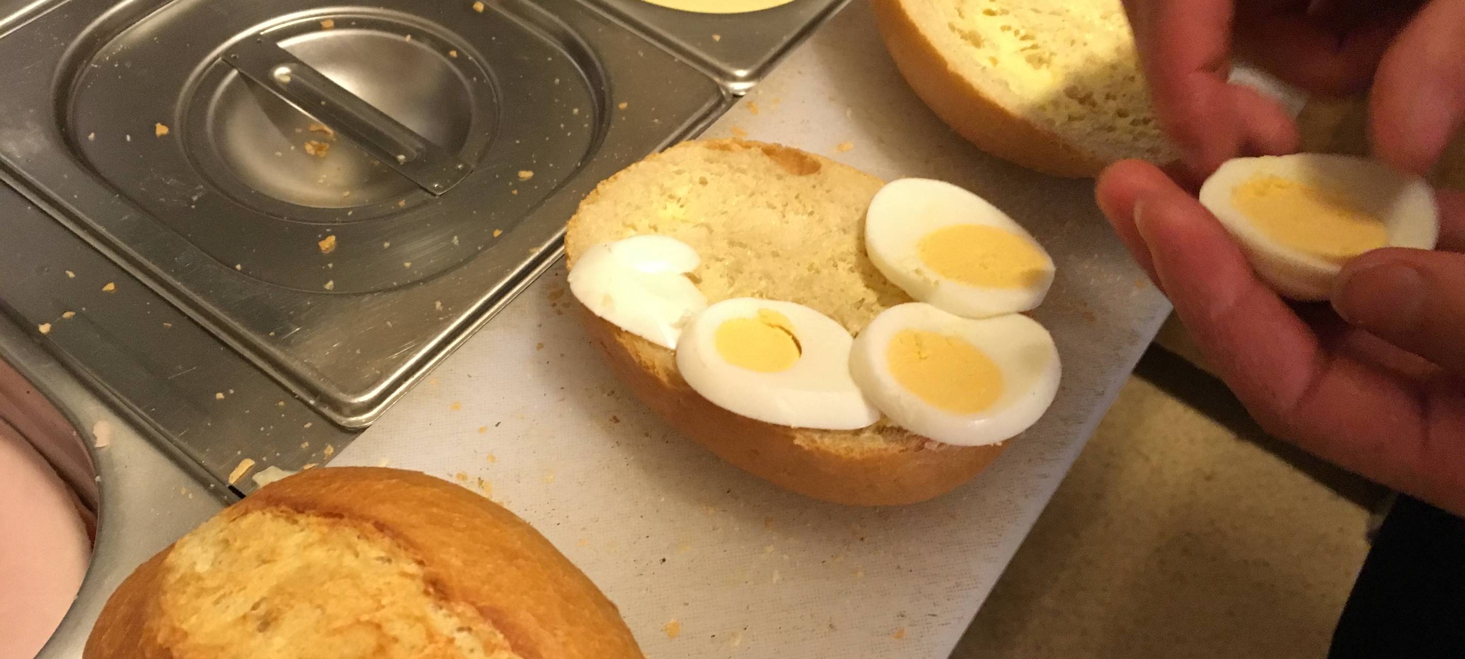 Brötchenschmieren in der Bäckerei Junker in Sundern-Hachen, hier ein Brötchen belegt mit quergeschnittenem Ei. Die Brötchen werden in drei Brötchenautomaten verkauft, die in zwei Sunderner Firmen stehen.