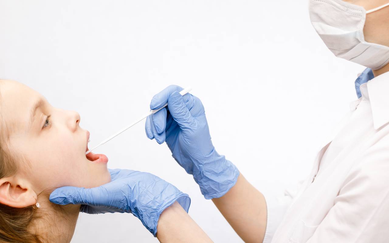 Arzt, der Speichelprobe aus dem Mund des Patienten entnimmt und dabei das diagnostische Verfahren für Speicheluntersuchungen durchführt.