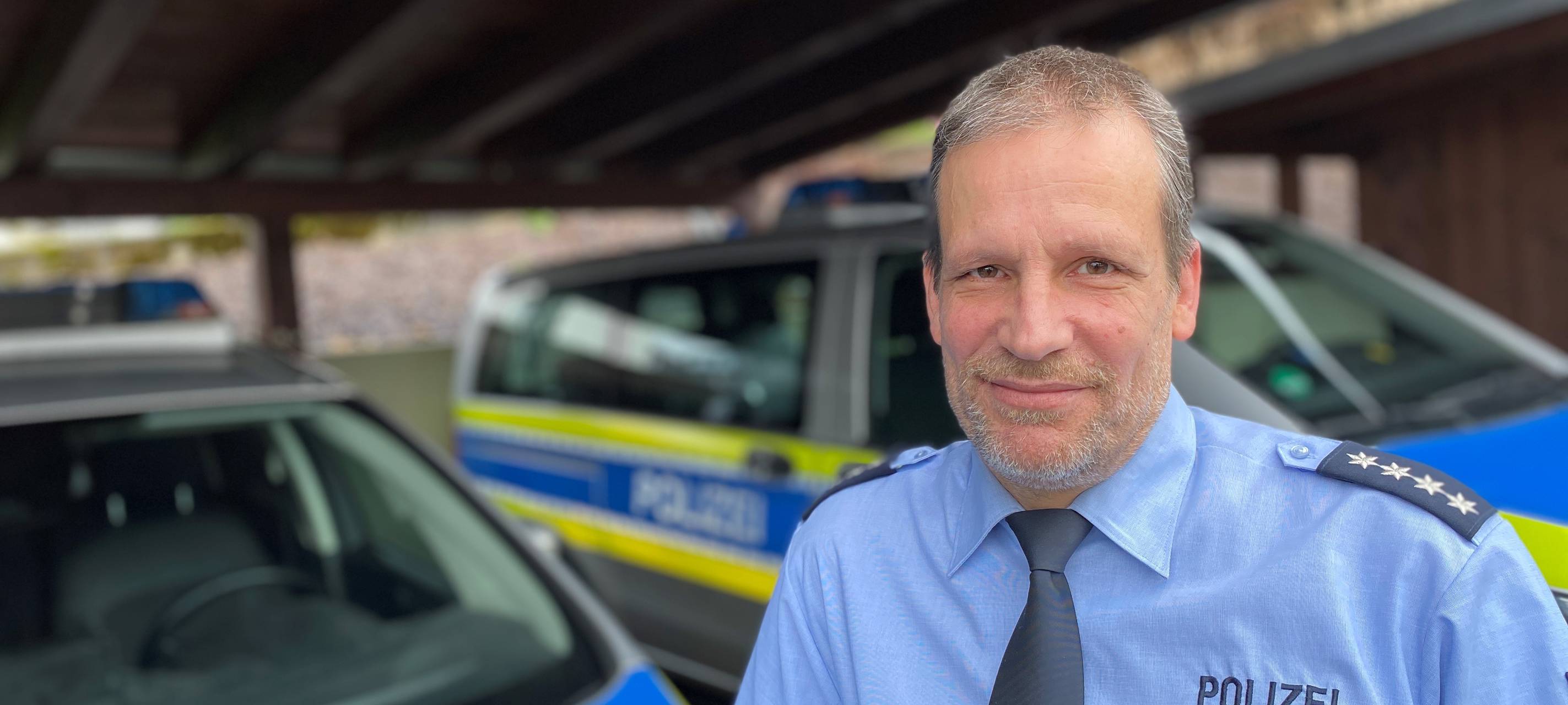 Polizeihauptkommissar Ludger Rath lehnt an einem Streifenwagen.