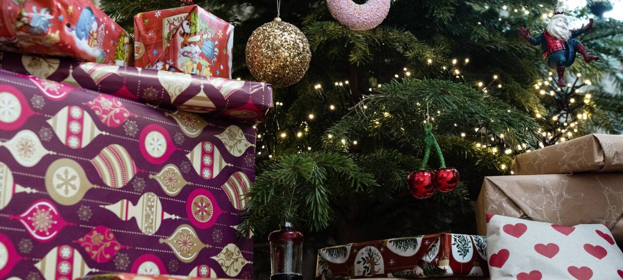 Eingepackte Geschenke liegen unter einem geschmückten Weihnachtsbaum.
