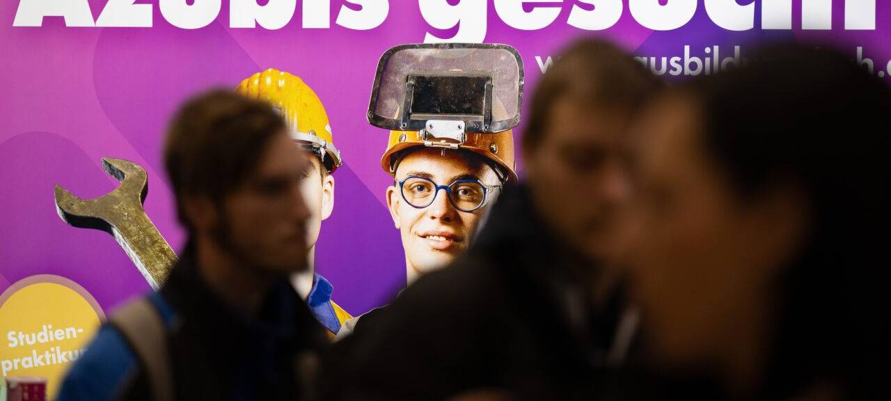 Besucher stehen auf der Jobmesse "KarriereStart" vor dem Schriftzug "Azubis gesucht"