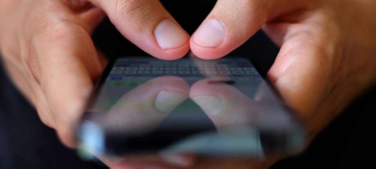 Ein Mann tippt auf einem Smartphone eine WhatsApp-Nachricht.