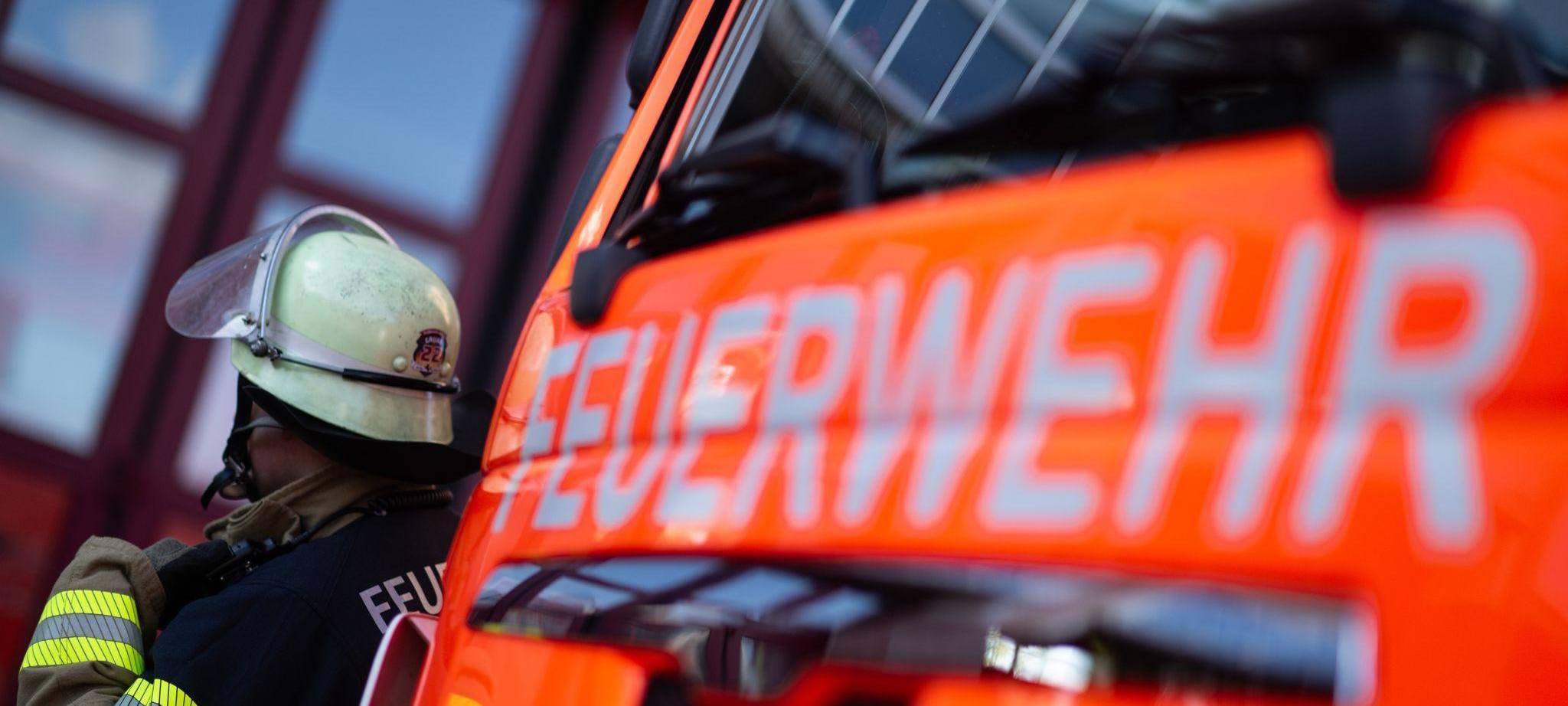 Feuerwehrmann steht neben einem Feuerwehrauto (Symbolbild)