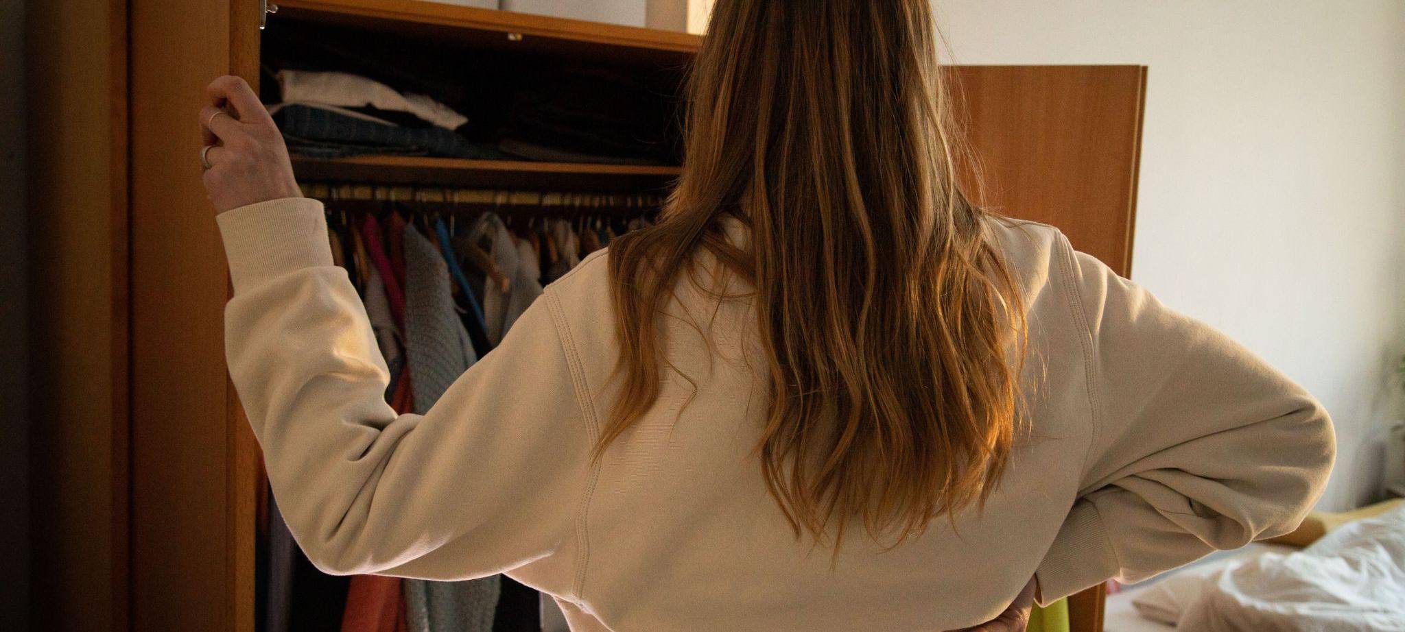 Eine Frau steht vor ihrem geöffneten Kleiderschrank