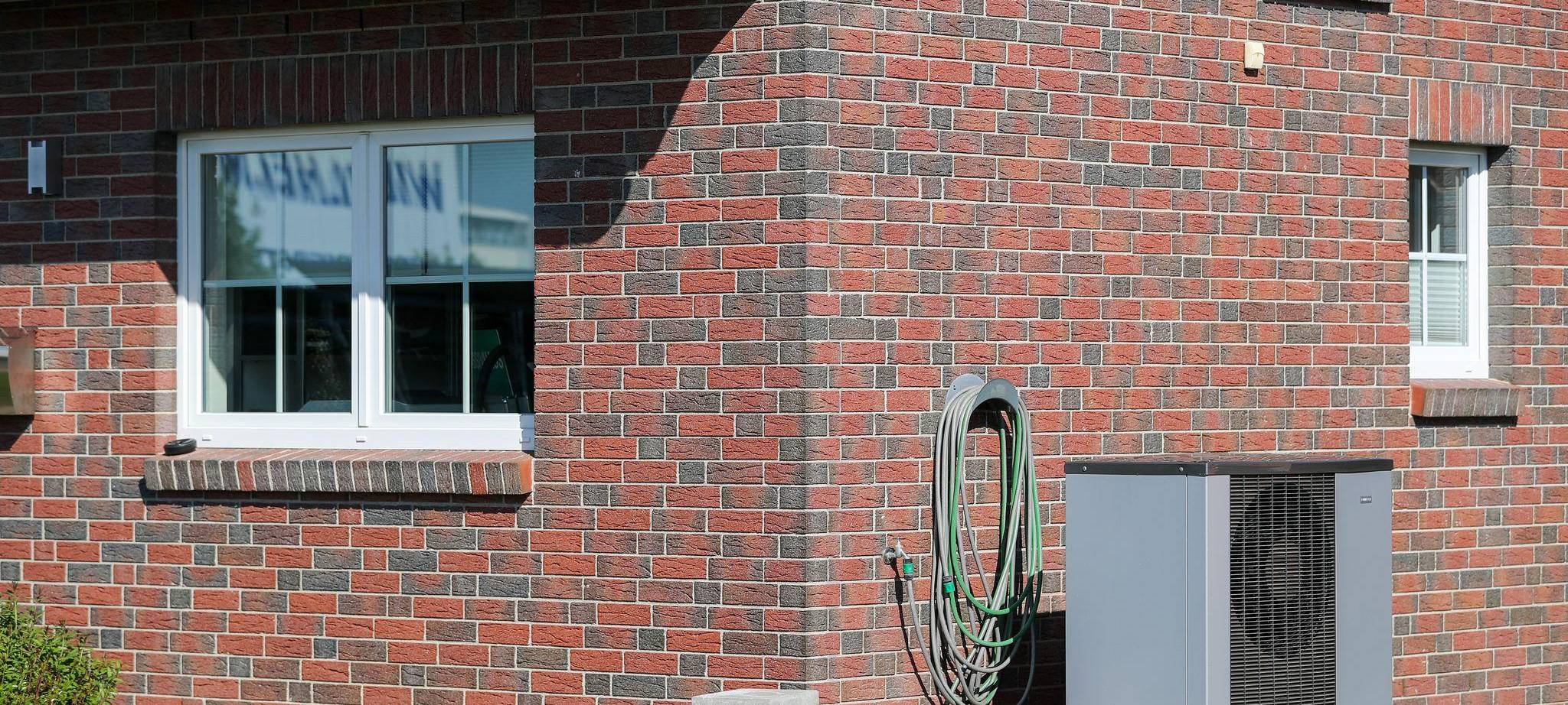 Eine Luft-Wasser-Wärmepumpe steht vor einem Haus